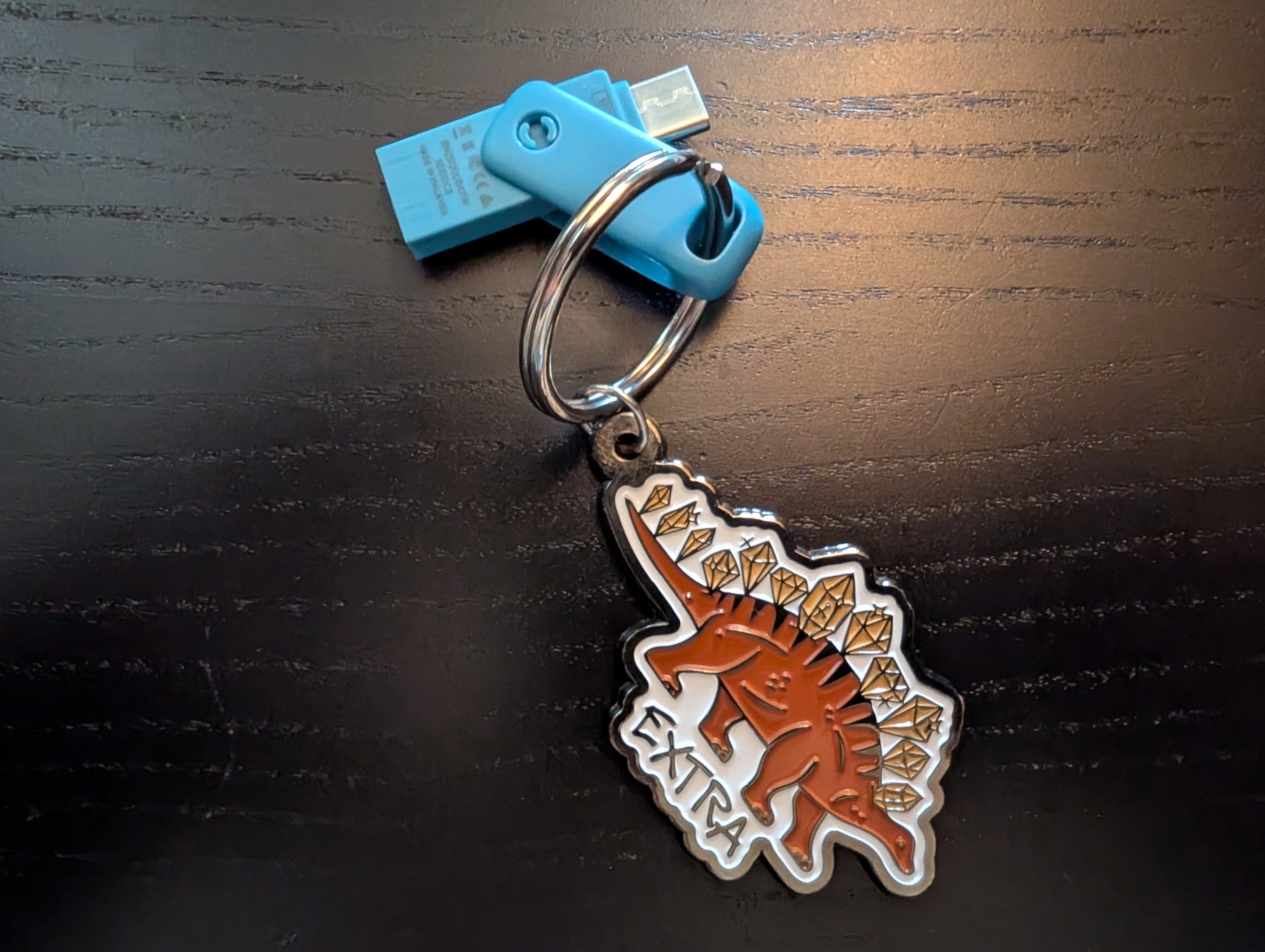 tiny blue USB attached to a keychain with an enamel stegasaurus with diamonds instead of plates and it says "extra"
